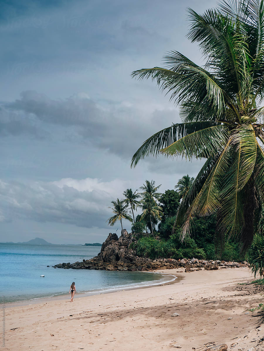 Girl on an empty beach with palmtrees