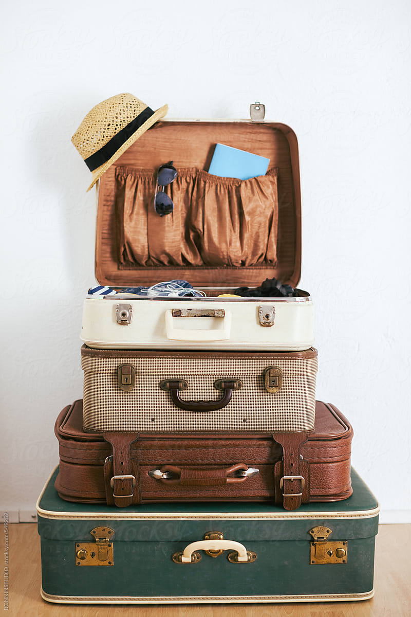 Stack of vintage suitcases with travel essentials.