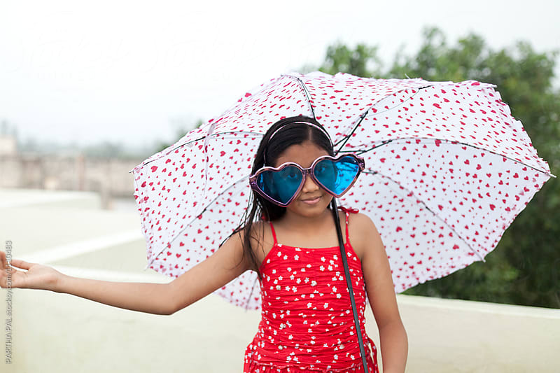 Teenage girl with fashionable spectacles and umbrella in rain
