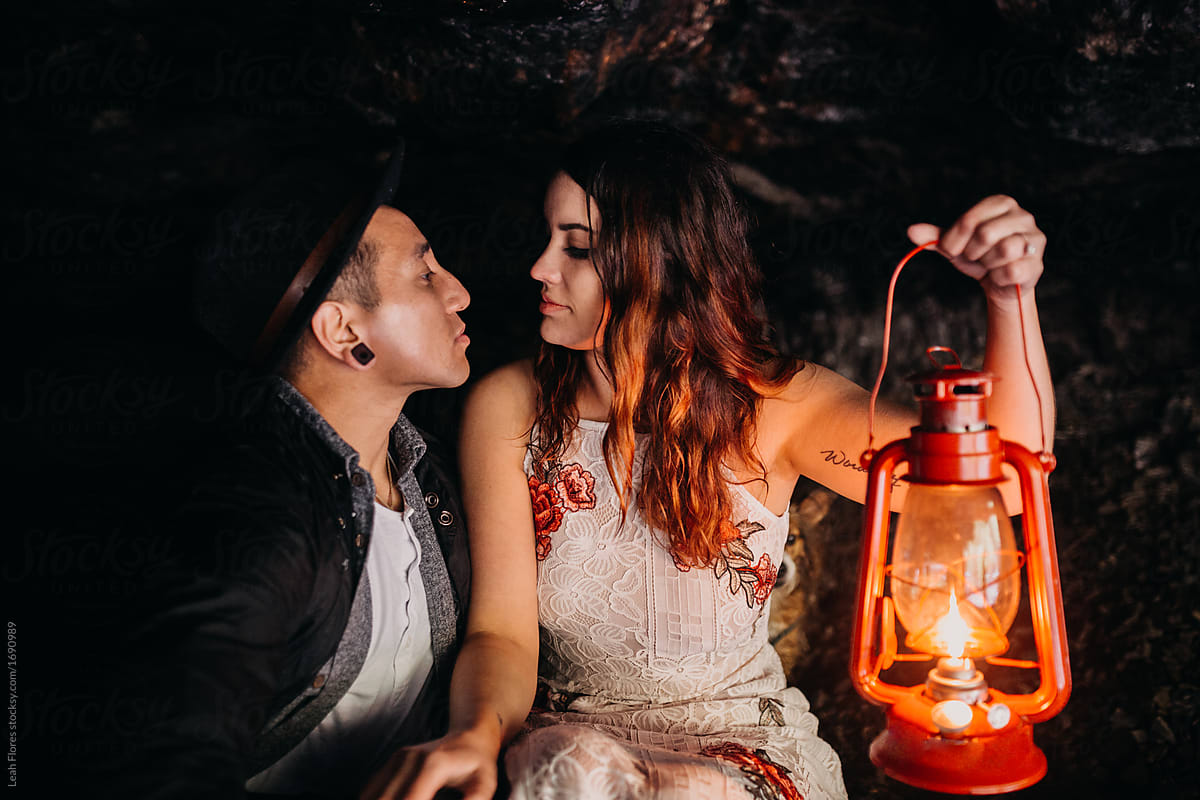 Couple Looking at each other while holding Lantern in Dark Cave