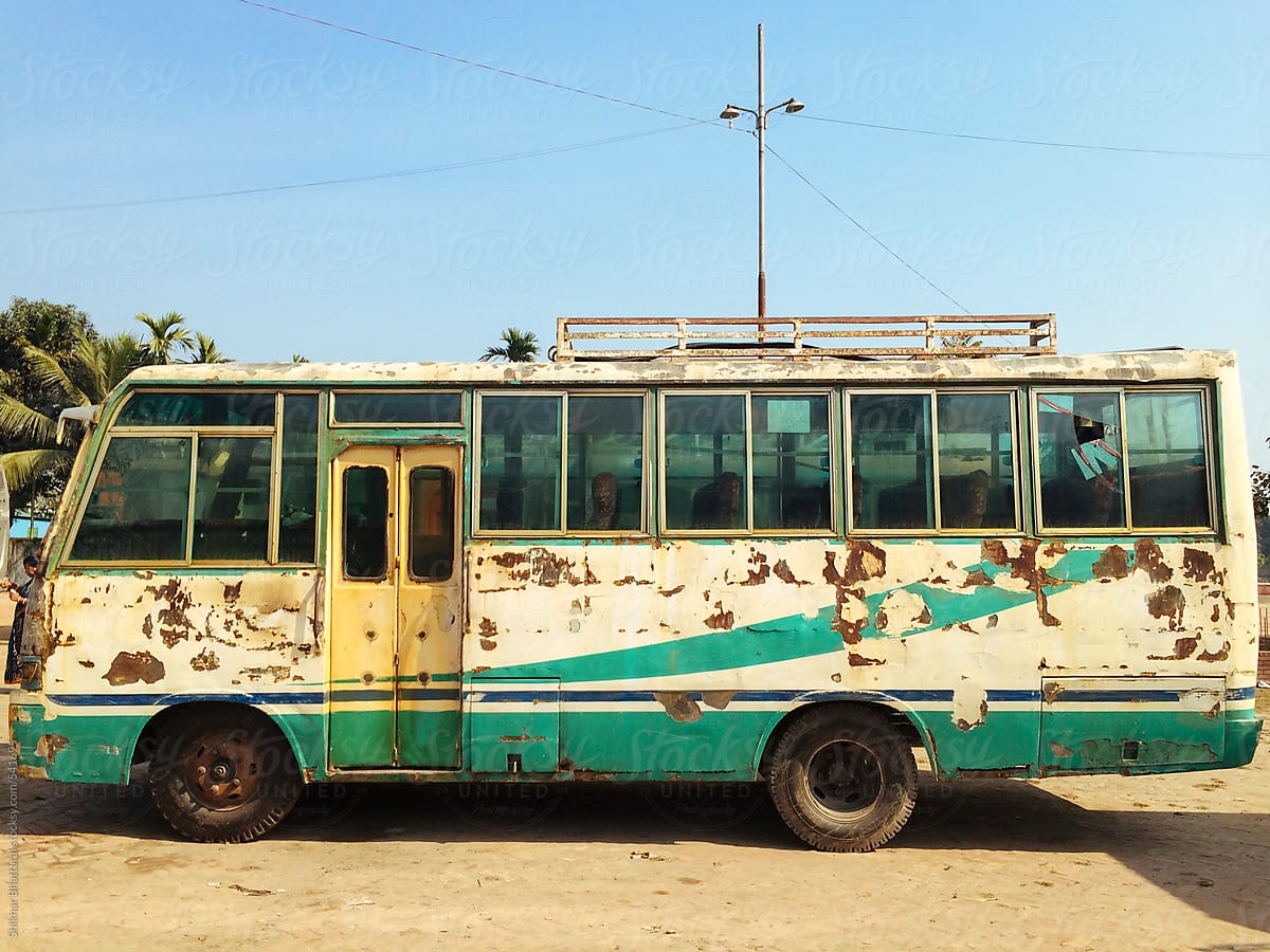 An old bus with scrape marks on the side.