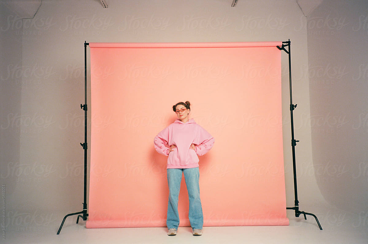 Young woman posing in front of peachy pink background in studio