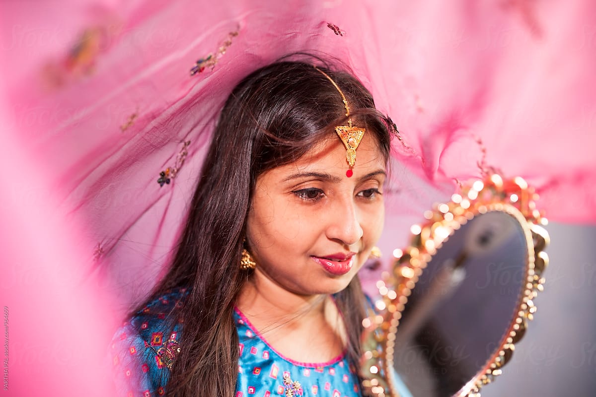 Young Indian woman with traditional dress and Jewelry and looking at the mirror