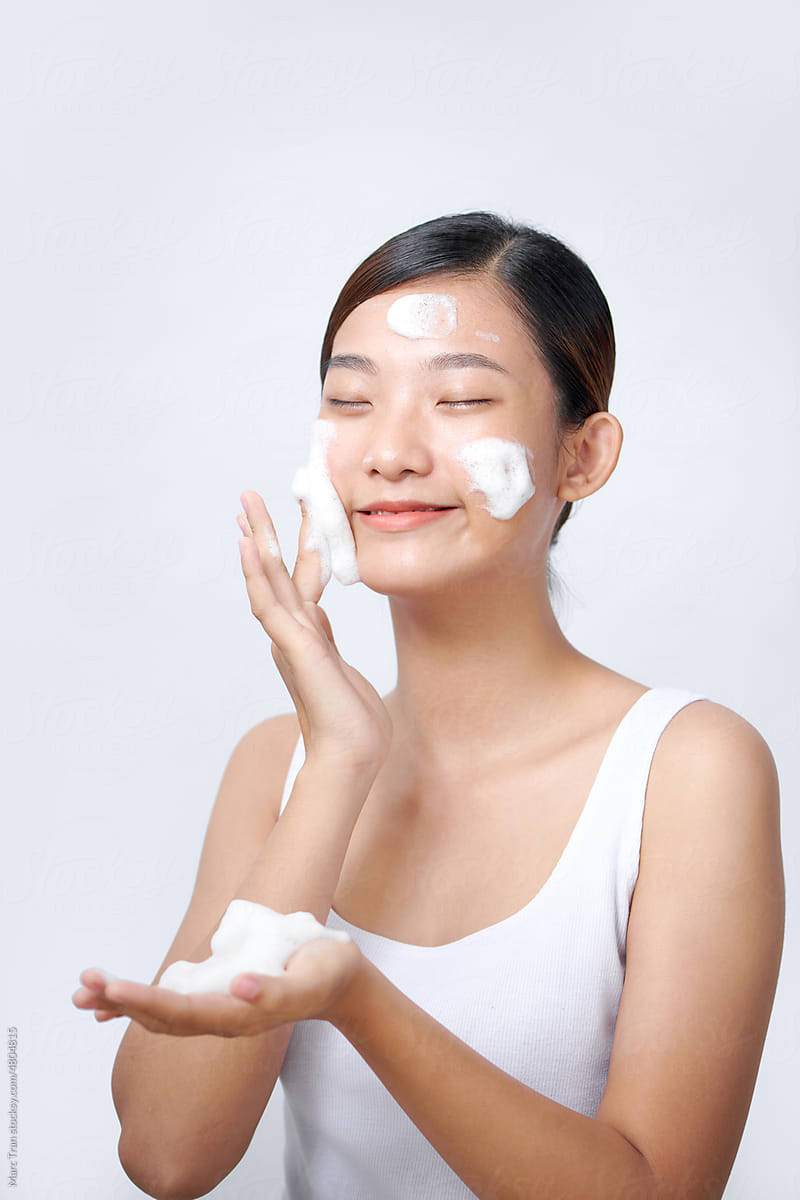 cute Asian girl scrub facial cleansing foam on her face