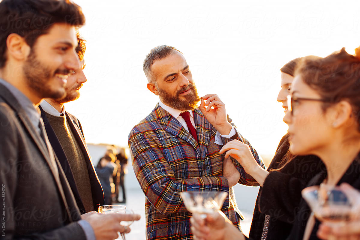 Crop glad coworkers conversing during party on rooftop