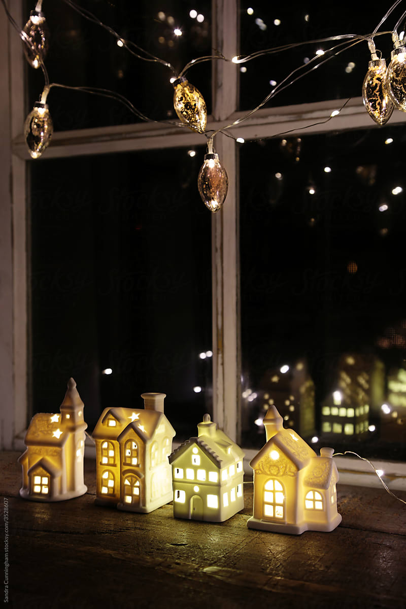 Gold lights hanging with little white houses in window