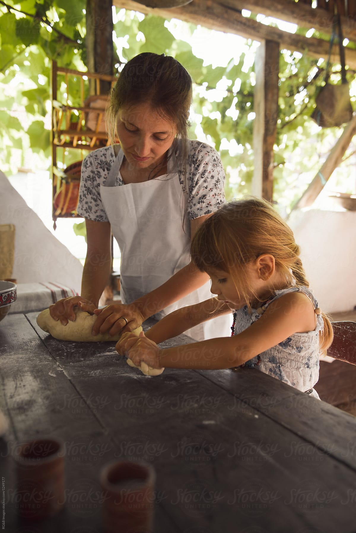 Mother and daughter preparing traditional bread outdoor on the p
