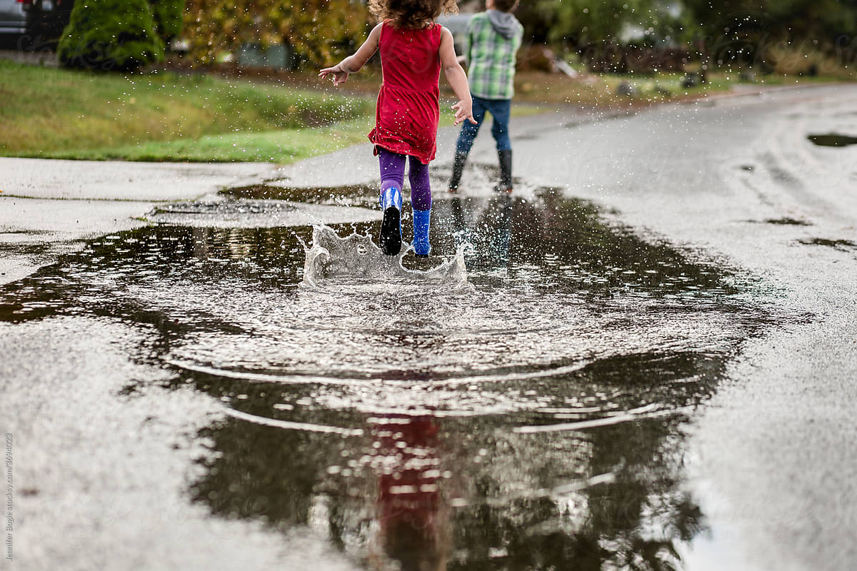 Girl chases brother through puddle