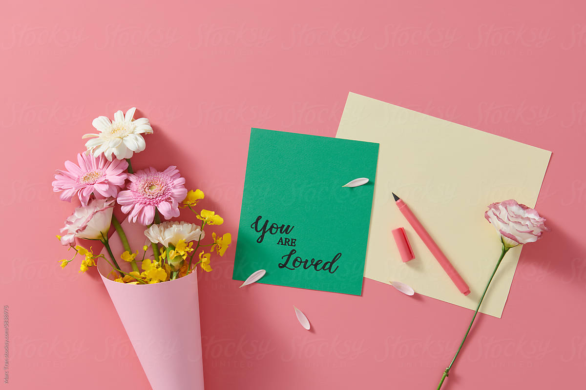 Bouquet of flowers in wrapping paper on pink with text You Are Loved