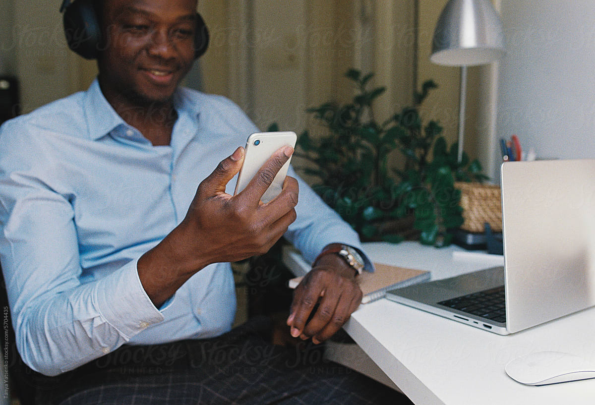 A man with a mobile phone sitting by the computer at home