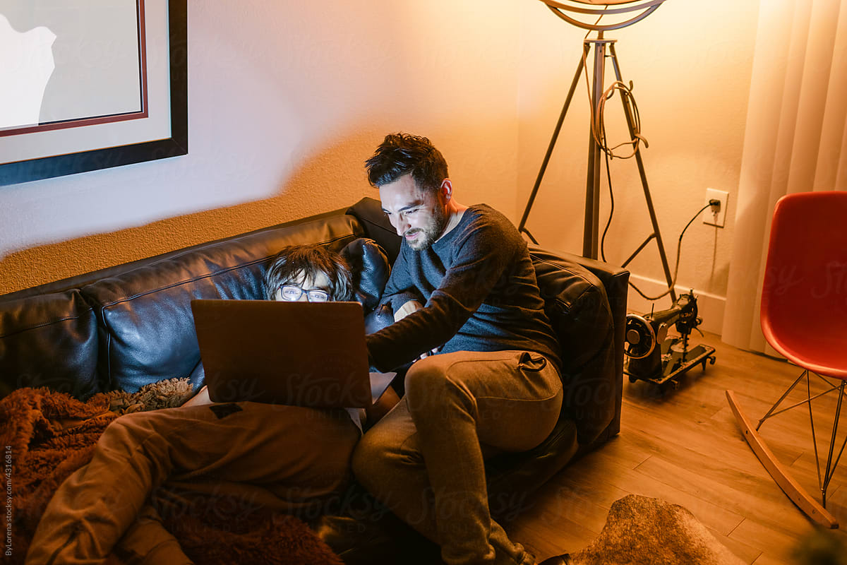 Father and teen son sharing laptop at night