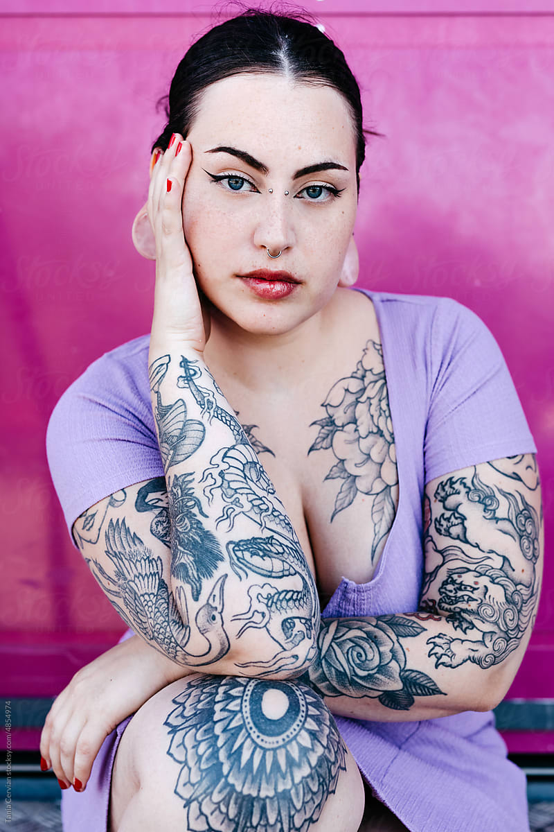 Stylish tattooed woman touching face