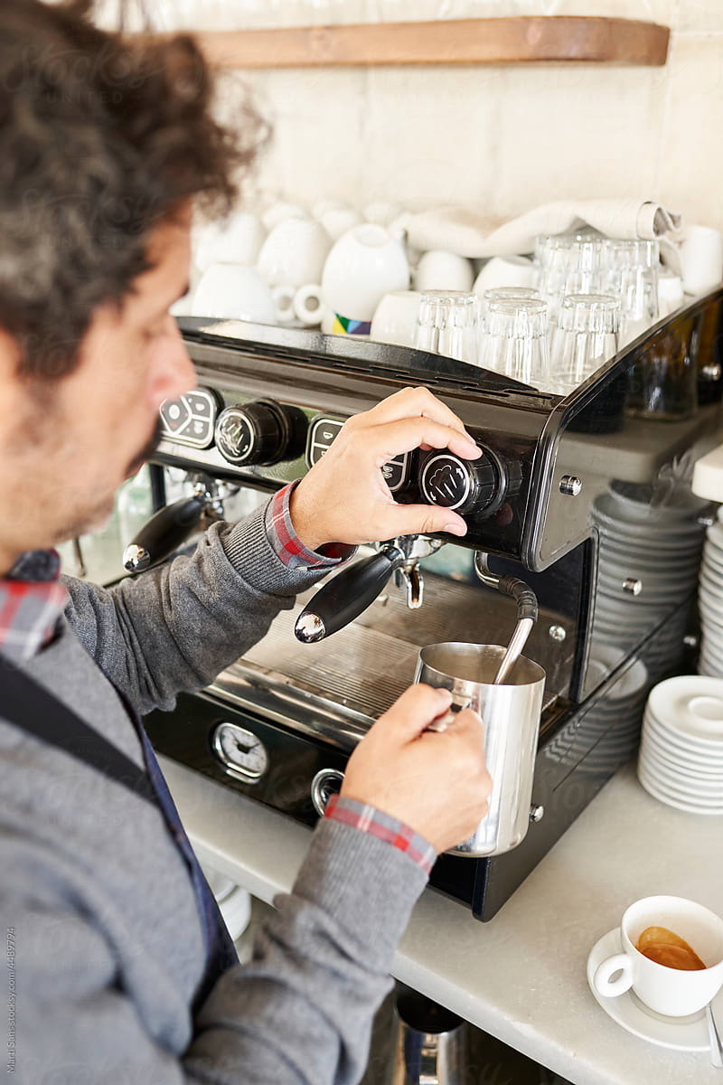 Barista pouring milk from coffee machine