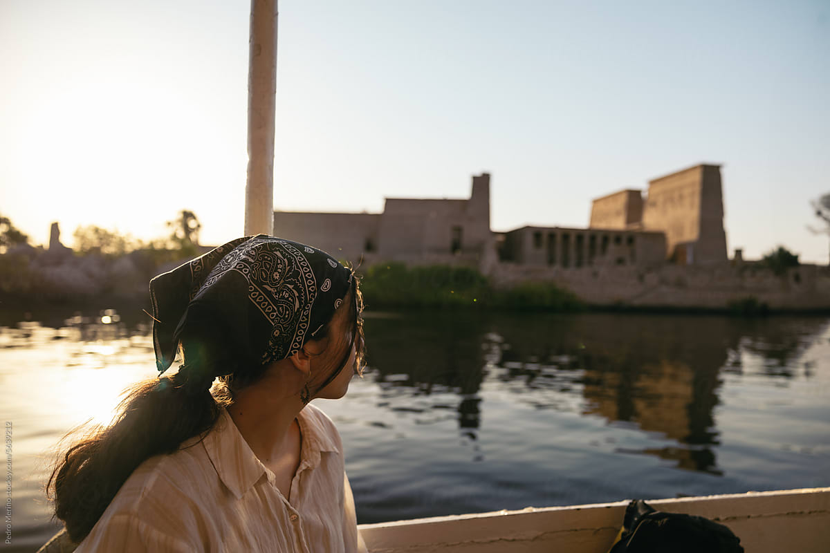 Woman observing Philae sailing on the Nile River in a boat