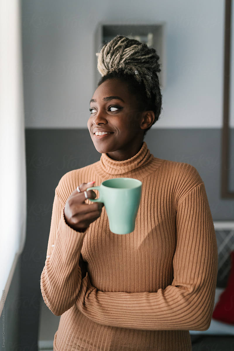 Content black woman with coffee cup at home