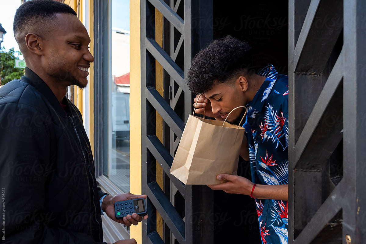 Black guy examining takeaway food near delivery man