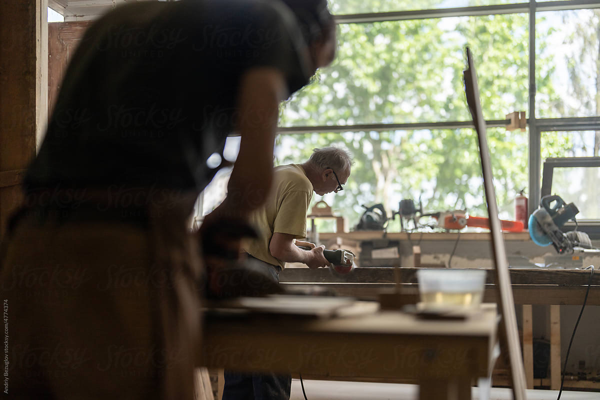 Two men renovating old wooden furniture alone at the workshop
