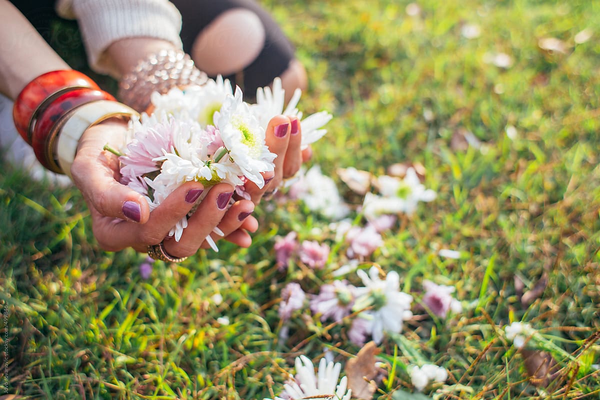 Woman kneeling and holding flowers over grass
