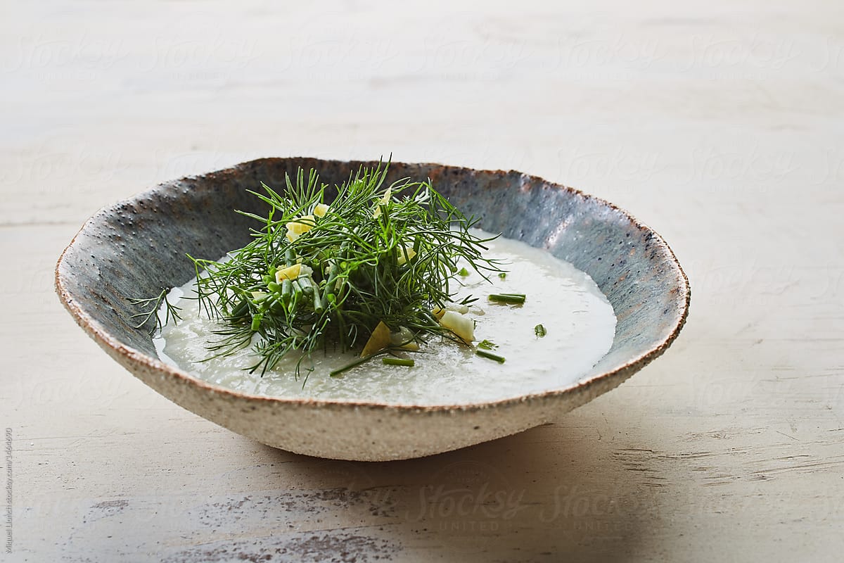 Fennel cream in a ceramic bowl with green\
 herbs