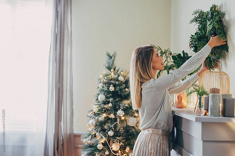 Woman Putting Christmas Wreath on The Wall