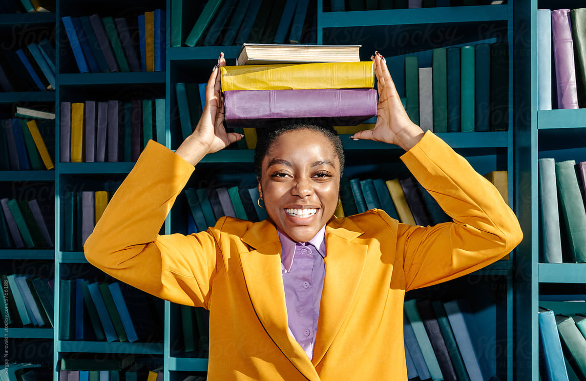 Smiling black woman with stack of books on head