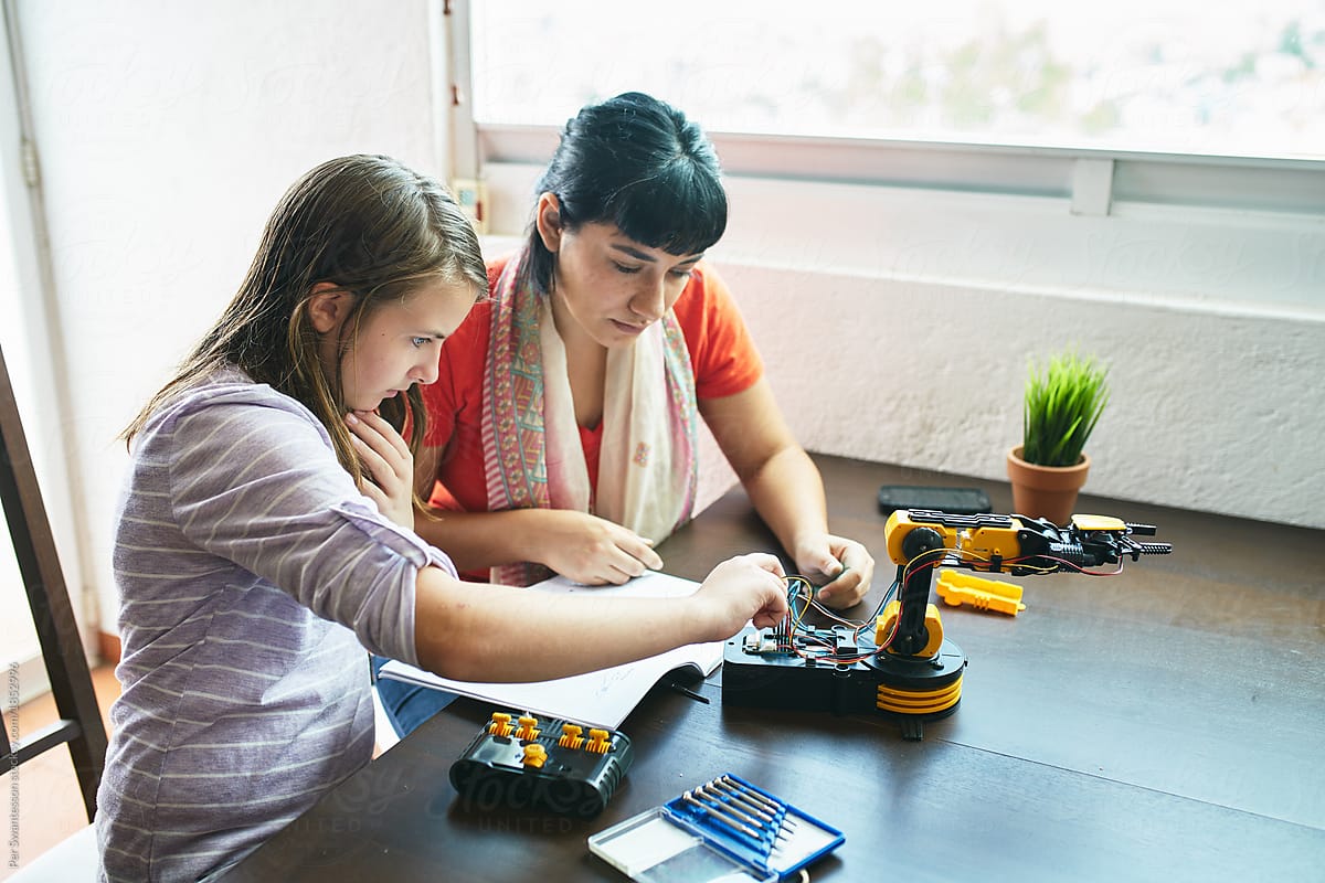 Young adult woman teaching a teenager science and robotics