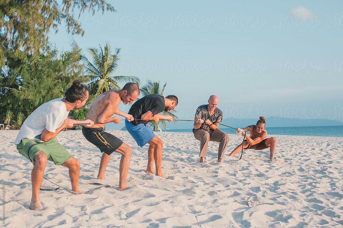 Guys Pulling Rope At The Beach by Stocksy Contributor Mosuno - Stocksy