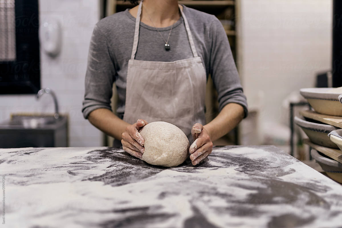 Woman working with dough in bakery.
