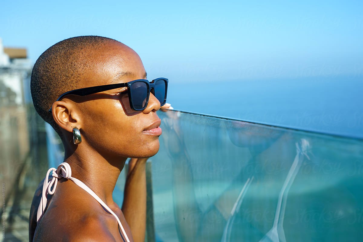 Trendy black woman with sunglasses enjoying ocean view