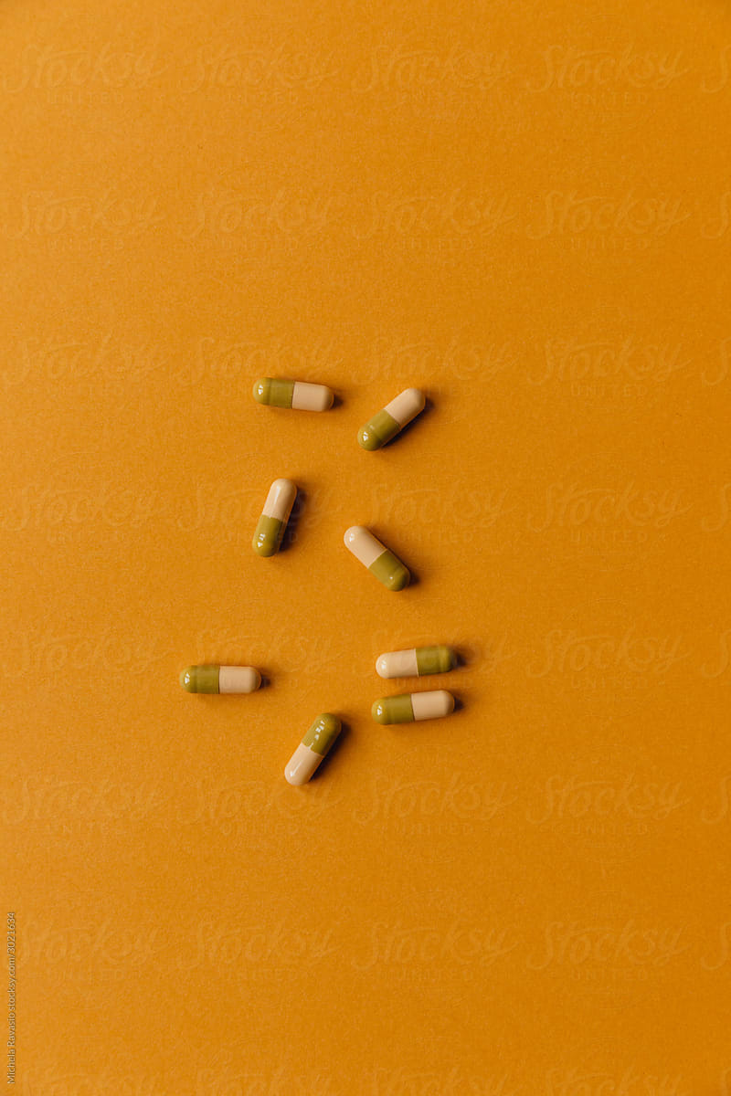 Bicolored capsules on mustard-colored background