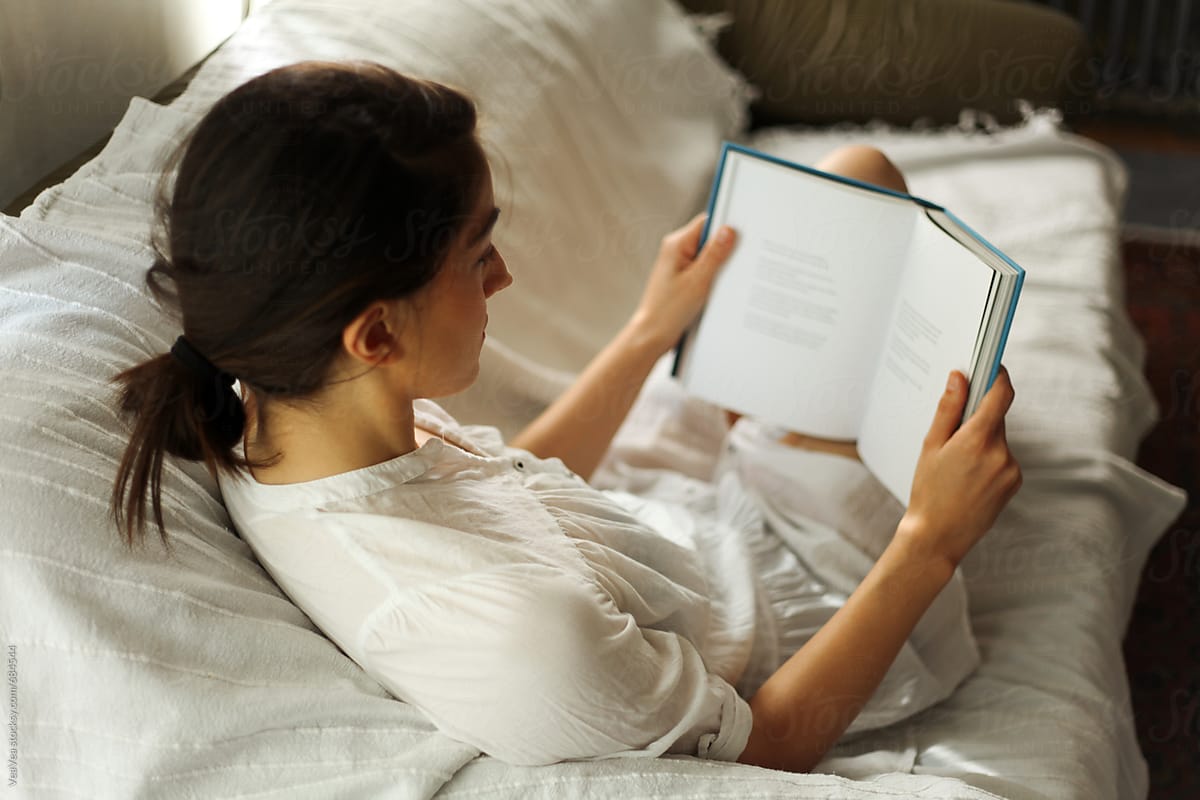 Woman Reading A Book On A Couch By Stocksy Contributor Mak Stocksy