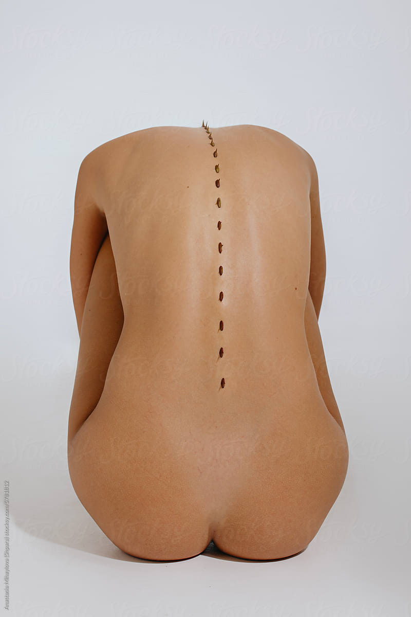 Close up photo of naked woman's skin of the back with thorns on spine
