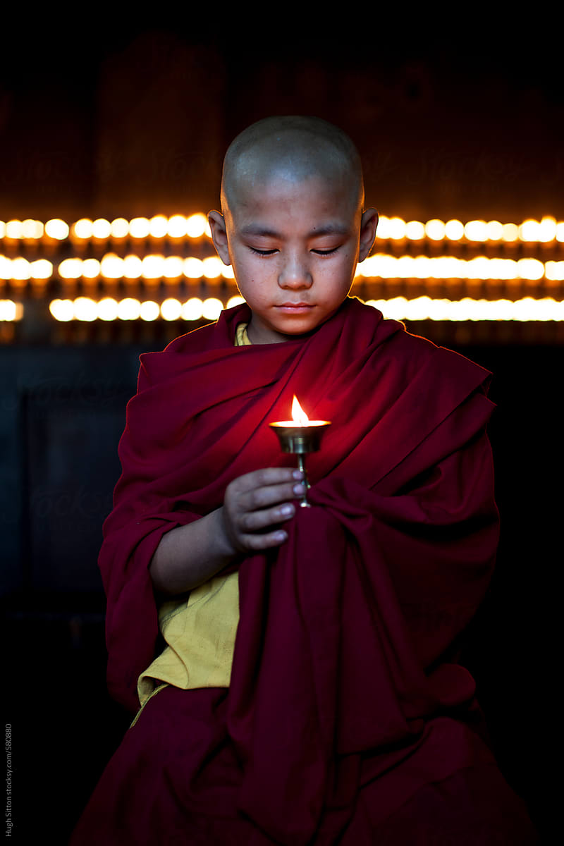 Novice monk holding candle.  India