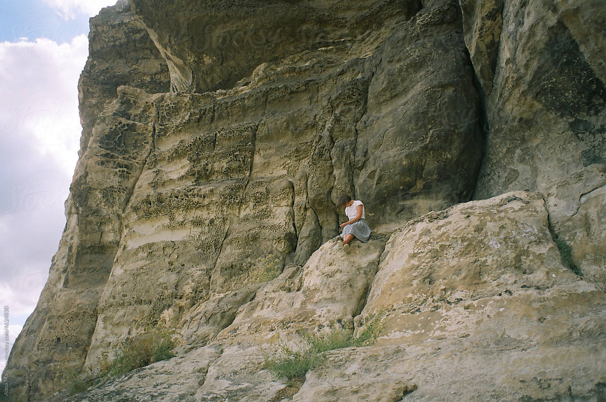 A woman sitting on a cliff in a mountains in Ukraine