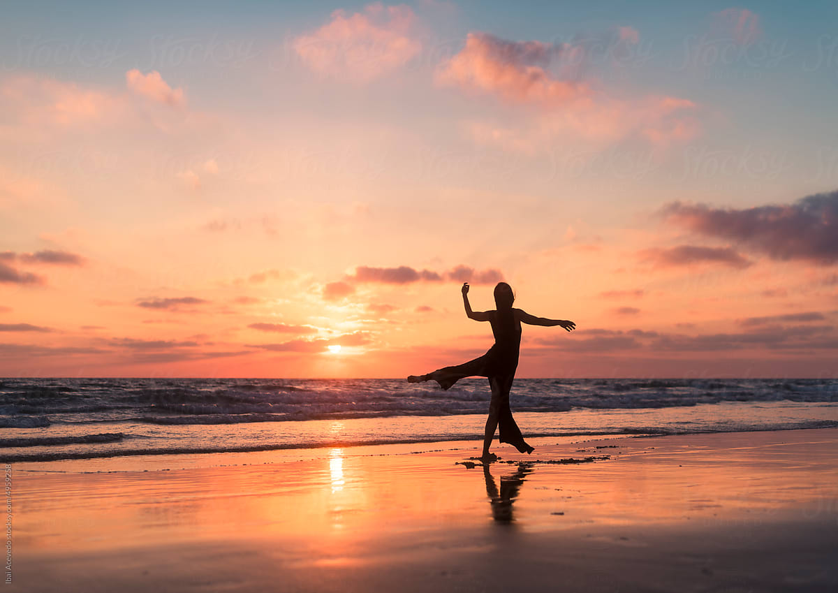 Dancing woman silhouette on sunset shore
