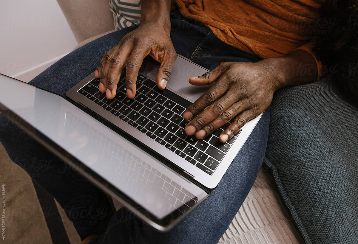 Anonymous black man\'s hands typing on modern laptop