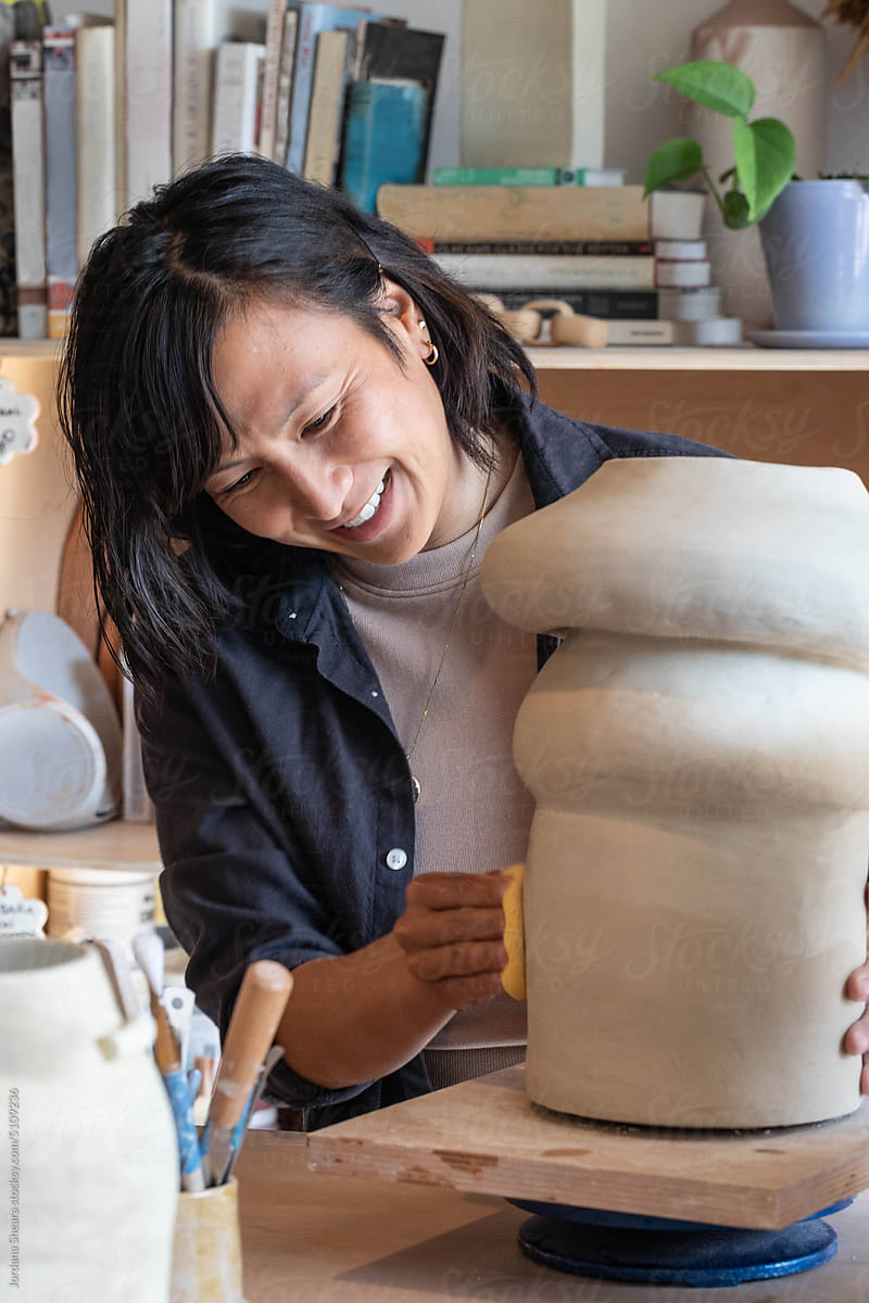 Asian woman working in the studio on a large piece of ceramics