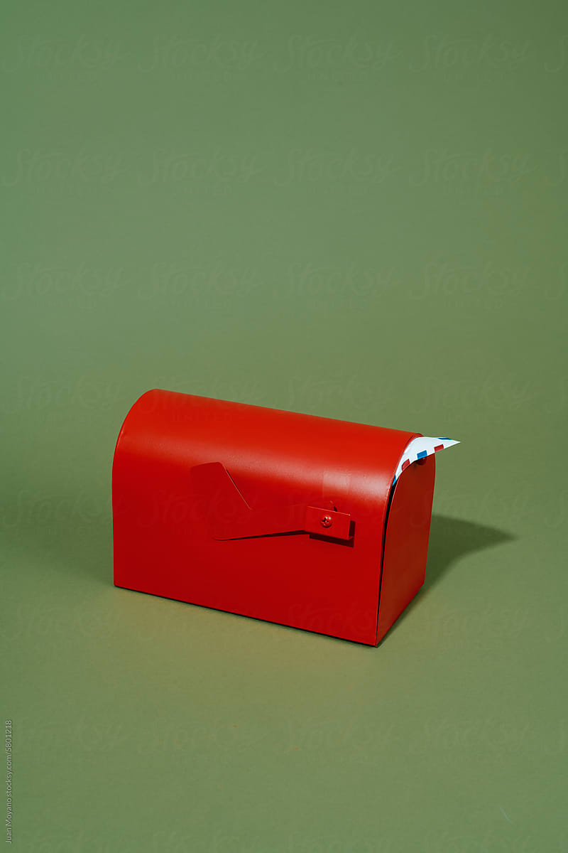 airmail letter peeps out from a red mailbox