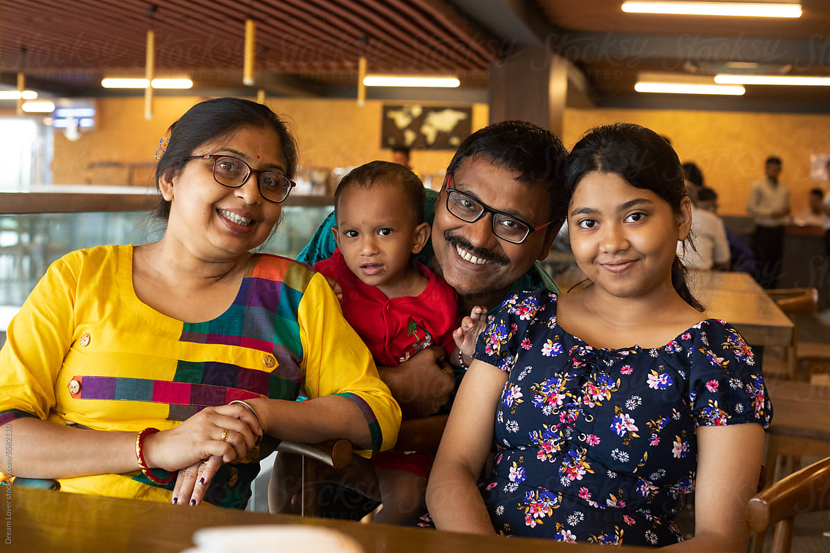 "Indian family photograph sit inside a restaurant in holiday time" by Stocksy Contributor "Dream Lover"