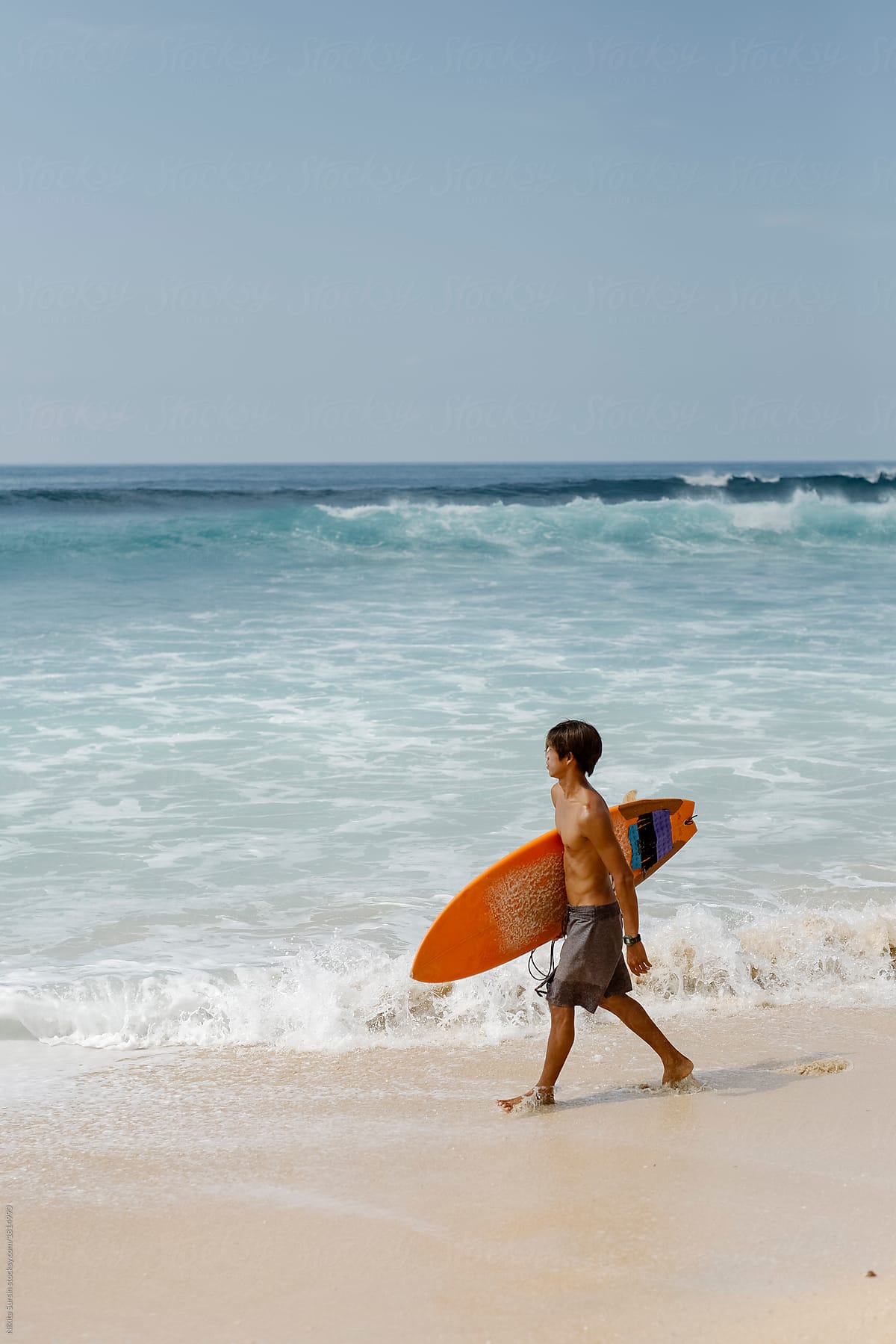 Young man with surfboard walking on the beach