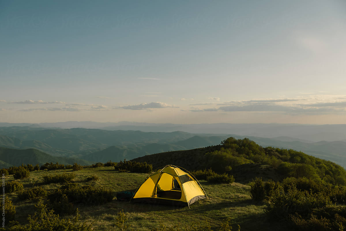 Camping tent on mountain top at sunset