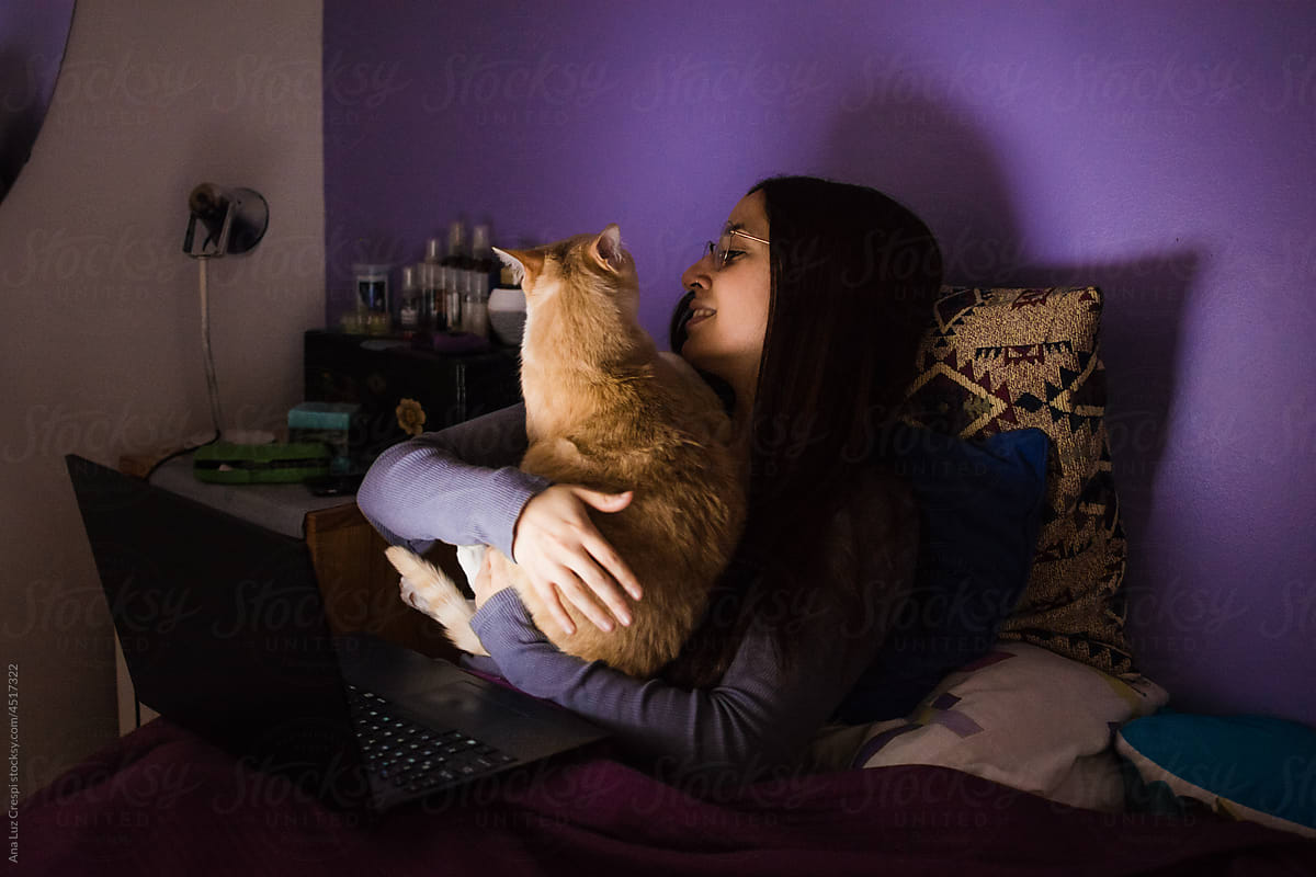 Woman and cat snuggling in bed at night