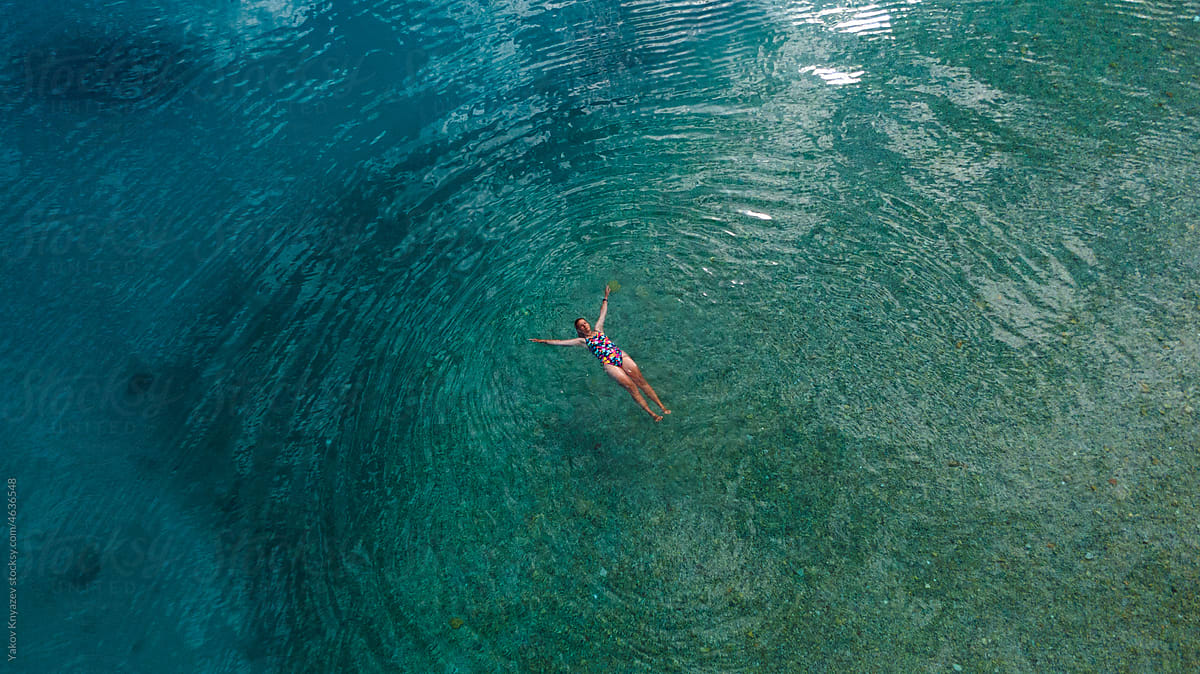 young woman relaxing on the sea surface, drone overhead