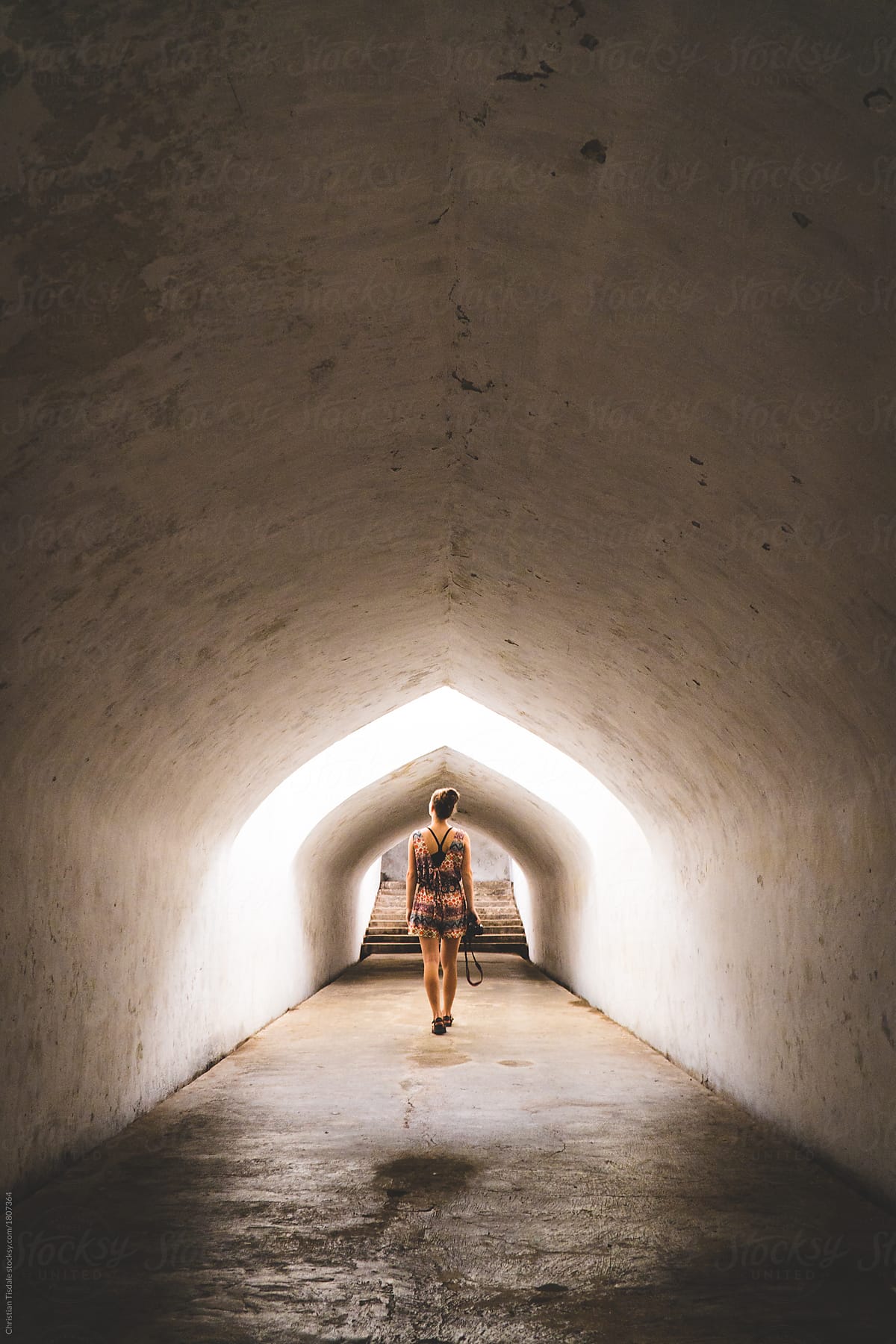 A young woman walking through a tunnel in an ancient palace