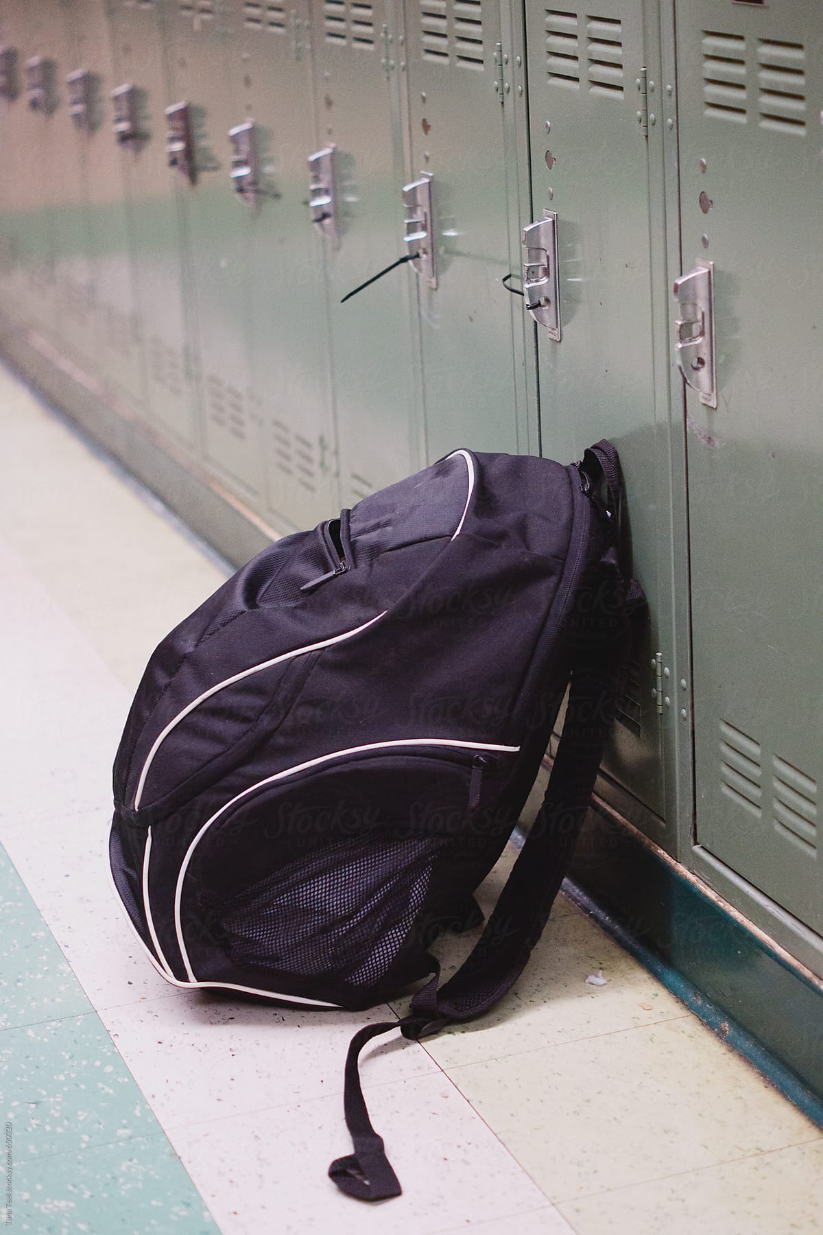 Backpack leans against a bank of lockers in a hallway