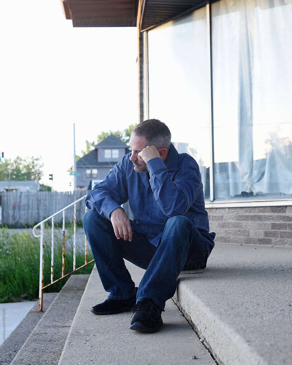 Sad Man Sitting on Steps Outside Closed Store