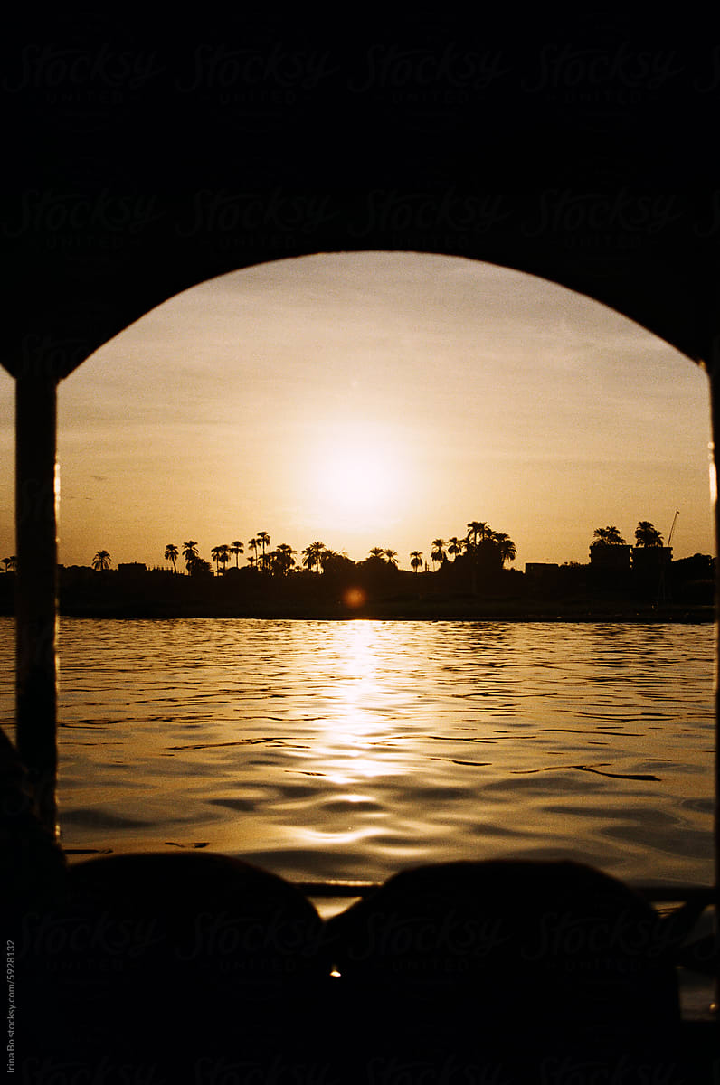 View of the golden sunset over the water through the arch of the yacht