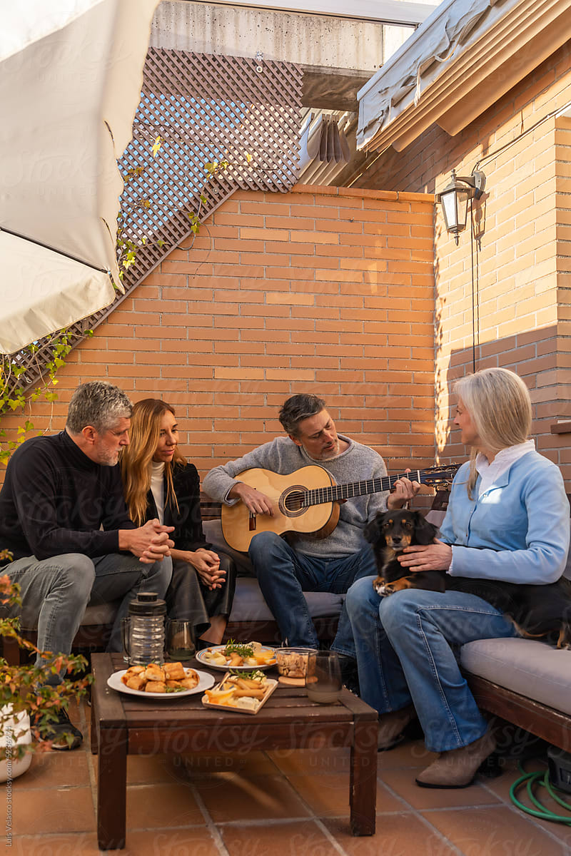 Bearded Man Plays The Guitar At A Gathering On A Terrace