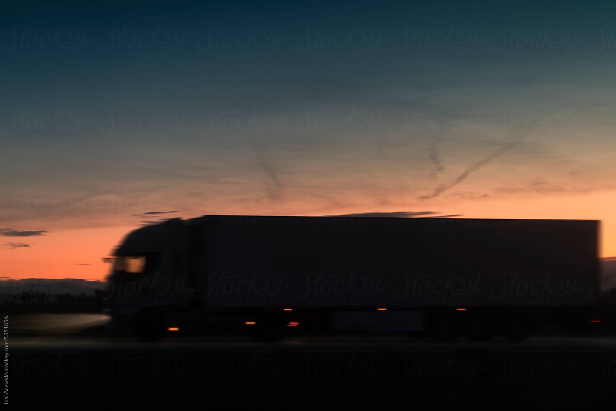 Truck travelling fast on dark road at sunset