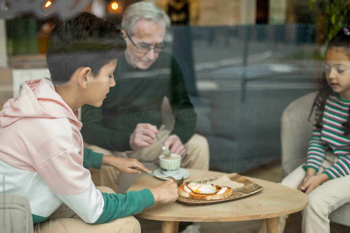 grandfather with his two grandchildren eating in a restaurant